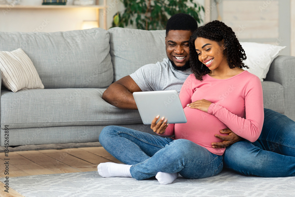Pregnant african american couple having fun at home, using digital tablet together, expecting black lady showing her husband baby room interiors, sitting by couch at living room, empty space Pregnant african american couple having fun at home, using digital tablet together, expecting black lady showing her husband baby room interiors, sitting by couch at living room, empty space