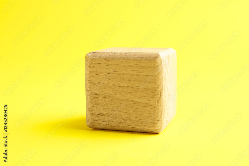 Fototapeta premium One blank wooden cube on yellow background, closeup