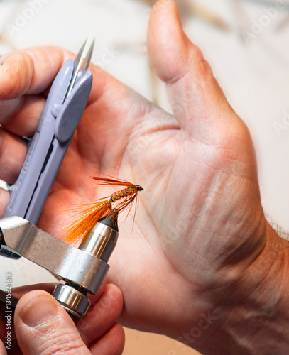 hand with fly tying tools and fishing fly