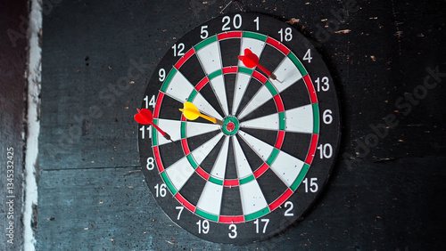 dart board hangs on a black wall with darts stuck into it