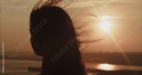 Woman hair blowing in wind at sunset by the river
