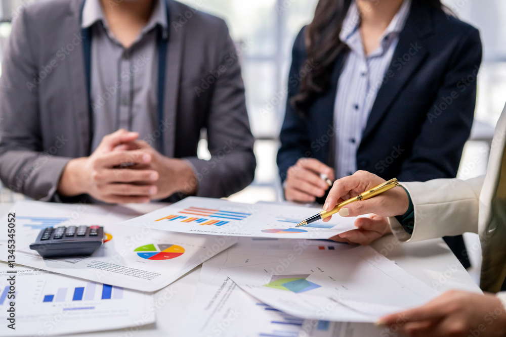 A group of people are sitting around a table with papers and a pen A group of people are sitting around a table with papers and a pen