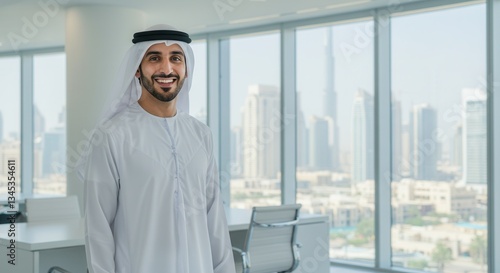 Smiling Emirati businessman standing in a modern office with a view of skyline.