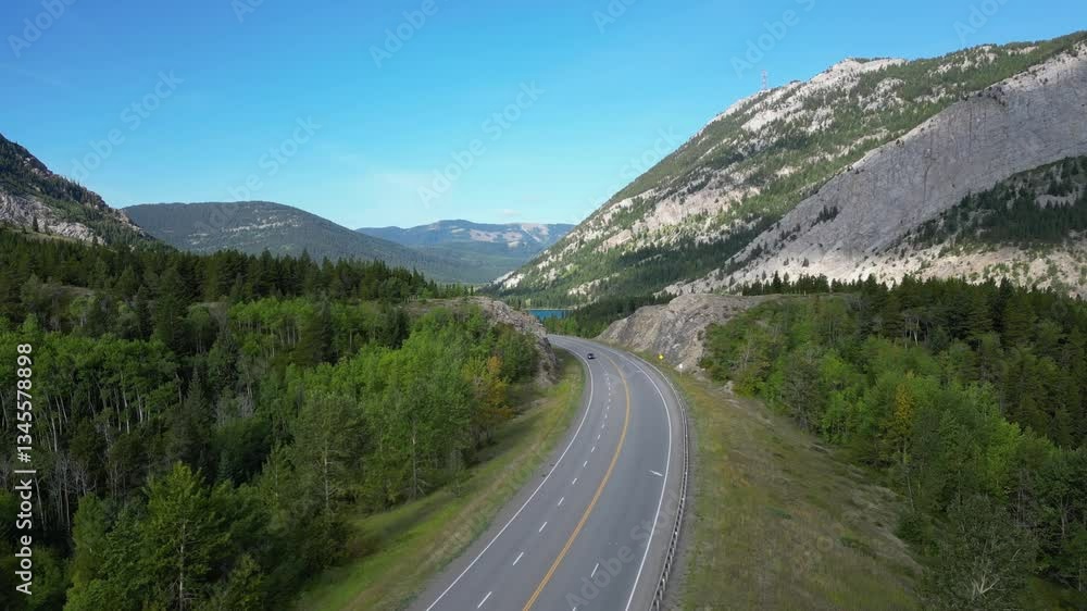 Aerial Drone View of Cars Driving on Winding Paved Road Through Mountain Valley Forest on Sunny Day Aerial Drone View of Cars Driving on Winding Paved Road Through Mountain Valley Forest on Sunny Day
