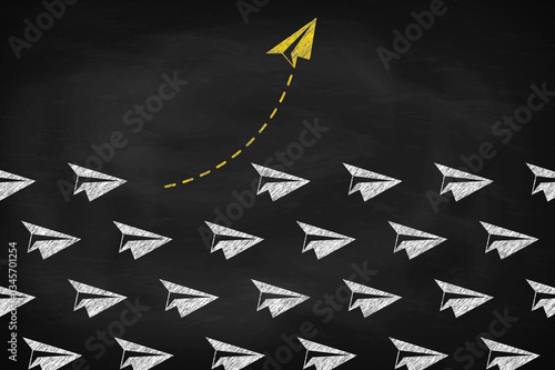 Yellow paper plane changing direction on black chalkboard. Think differently concept