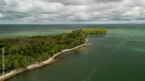 Wallpaper Mural Aerial drone footage of a lush green peninsula extending into a calm body of water, with a narrow sandy shoreline and a cloudy sky above Torontodigital.ca