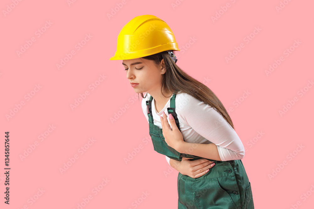 Female builder having heart attack on pink background Female builder having heart attack on pink background