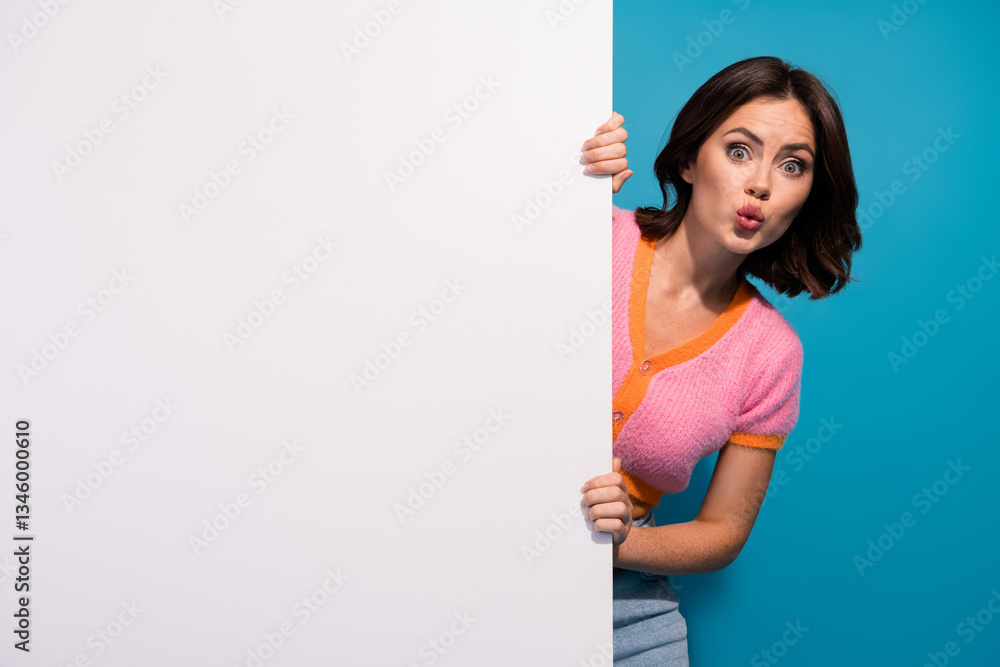 Surprised Young Woman Peeking Out Behind Blank White Panel with a Playful Gesture on Colorful Background Surprised Young Woman Peeking Out Behind Blank White Panel with a Playful Gesture on Colorful Background