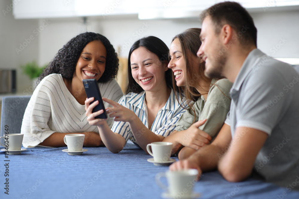 Happy interracial friends using phone in the kitchen Happy interracial friends using phone in the kitchen