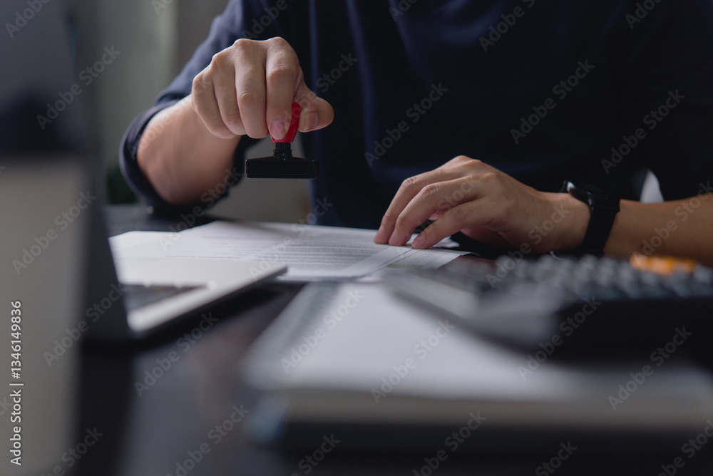 Fototapeta premium A business professional stamping an official document in an office environment, symbolizing document approval and business paperwork processes.