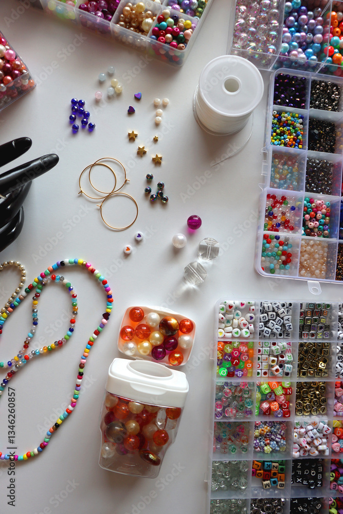 Hand figurine, colorful friendship bracelets, necklaces, various beads and DIY supplies on the table. Making jewelry at home. Flat lay.