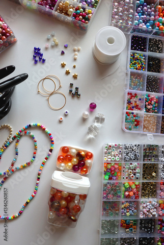 Obraz na płótnie Hand figurine, colorful friendship bracelets, necklaces, various beads and DIY supplies on the table. Making jewelry at home. Flat lay. w salonie