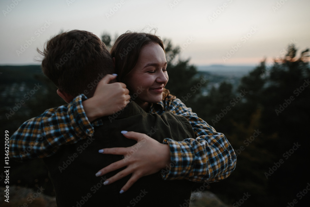 Fototapeta premium Beautiful young woman in the arms of her boyfriend at sunset in the mountains.