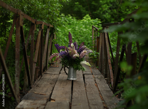 beautiful spring view.A bouquet of lupins stands on an oldwooden bridge above a small forest river.