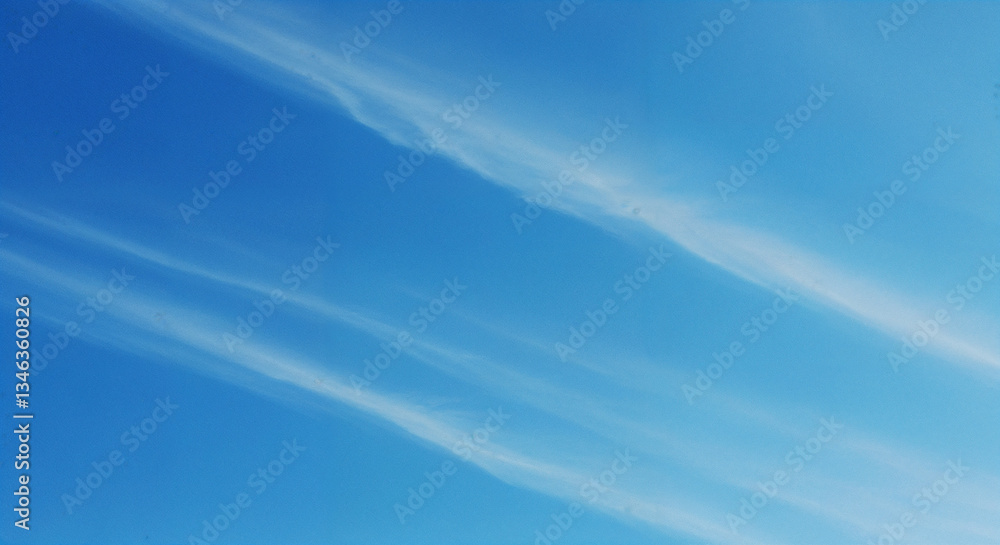 Diagonal white cirrus clouds in bright blue sky, Gentle wispy streaks across azure atmosphere, Natural weather pattern background for meteorology and tranquility themes Diagonal white cirrus clouds in bright blue sky, Gentle wispy streaks across azure atmosphere, Natural weather pattern background for meteorology and tranquility themes
