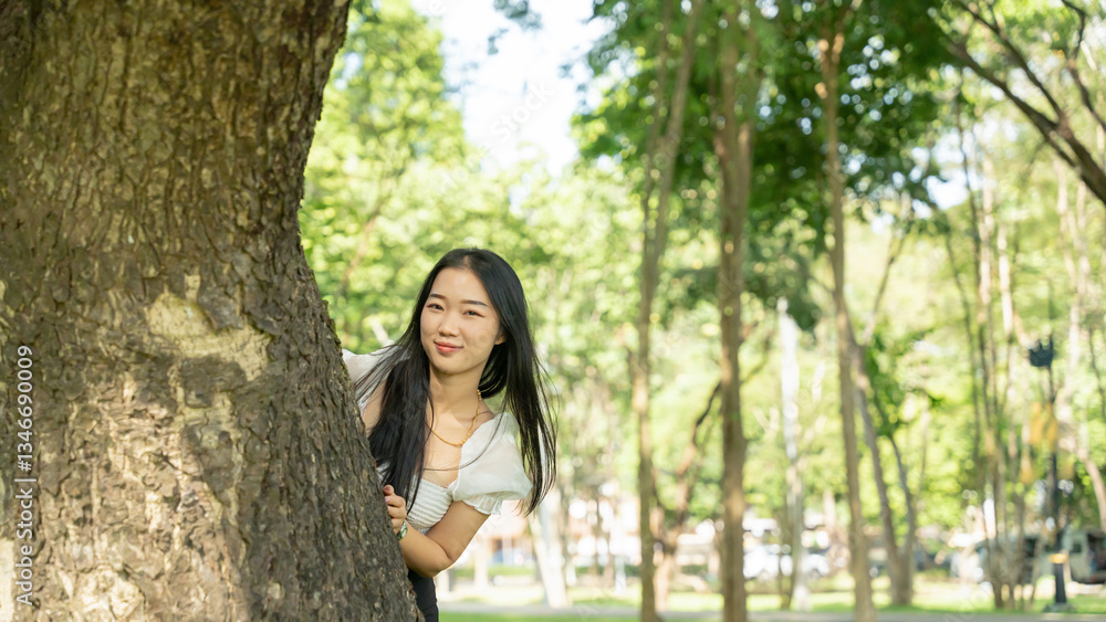 Beautiful girl peeking out from behind a tree in the park. Beautiful girl peeking out from behind a tree in the park.