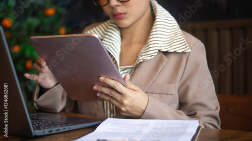 Wallpaper Mural Businesswoman is managing financial information on tablet and working on laptop at the same time on desk and documents in office. Torontodigital.ca