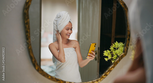 Photography Indian happy gen z young adult female lady wrapped towel head and body use mobil