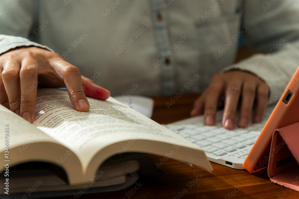 A student studying at night, typing on a keyboard with books open in front of them A student studying at night, typing on a keyboard with books open in front of them