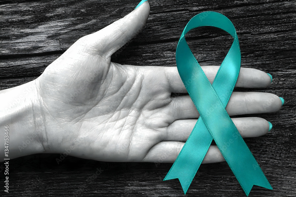 Teal ribbon in hand, awareness, support, dark wood background. Possible use for cancer awareness campaign