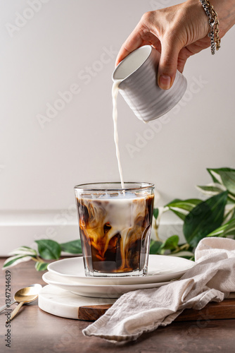 Φωτογραφία milk being poured into a glass of iced coffee, creating delicate swirling patterns