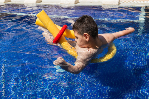 Child with cerebral palsy swimming in pool with floatation devices