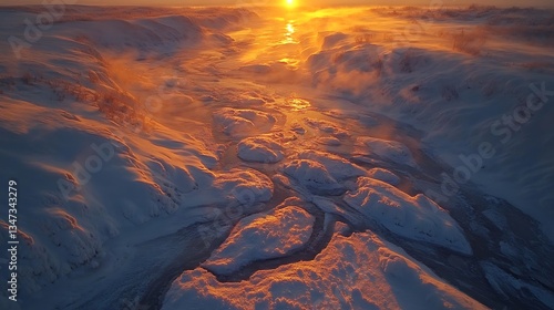 Aerial view of a frozen river winding through snow-capped mountains at sunset.  Possible use  Stock photo