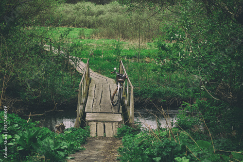 vintage bike on the old wooden bridge over small forest river.spring mood