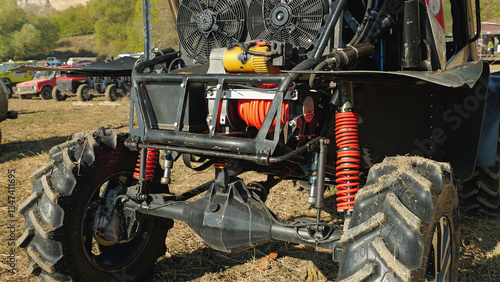 Close-up of a custom-built off-road vehicle with large tires, a powerful engine, and a roll cage. The vehicle is equipped with a winch and other modifications for extreme off-roading.