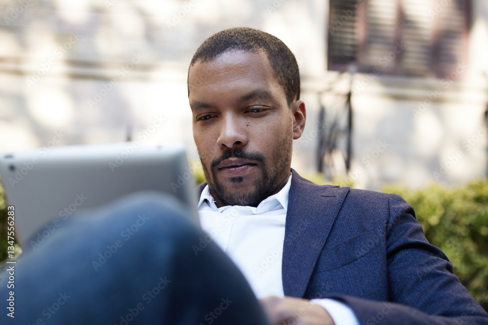 Naklejka premium African American young businessman wearing blue suit posing outdoor and looking away.