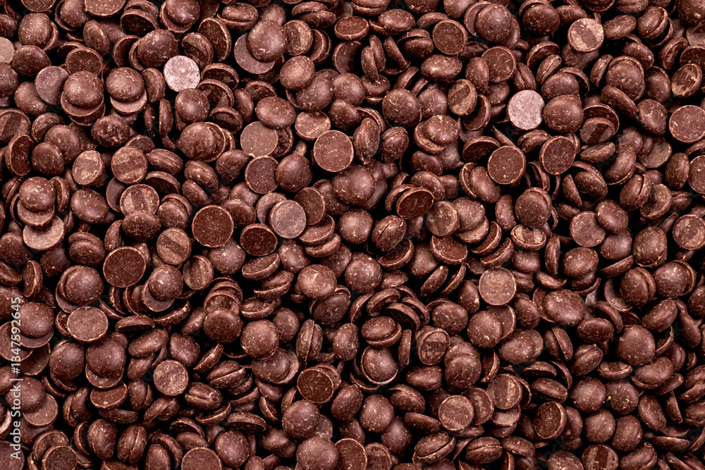 Fototapeta premium Dark Chocolate Drops Top View.A top-down view of dark chocolate callets (drops) scattered on a neutral background