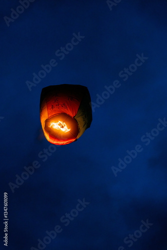 Floating Chinese lantern with wishes in the night sky photo