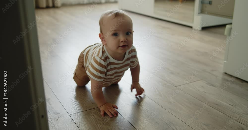 Cute toddler crawling on all fours towards the camera on the bedroom floor. A one year old child explores the world around him. Slow motion medium shot.