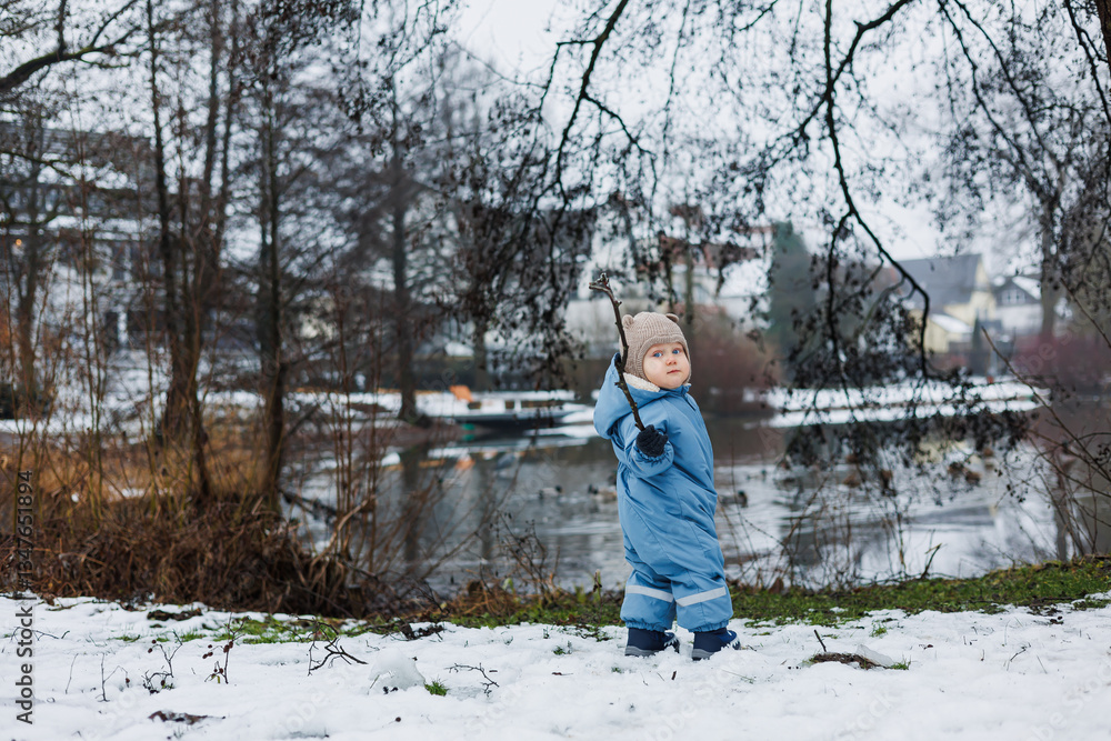 A joyful child is playing happily in a snowy winter landscape near the lake, surrounded by the picturesque beauty of nature and the serene qualities of the snowcovered environment A joyful child is playing happily in a snowy winter landscape near the lake, surrounded by the picturesque beauty of nature and the serene qualities of the snowcovered environment