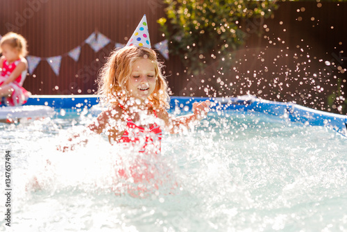 Blonde curly-haired 6-7-year-old girl swimming in a backyard pool during summer, celebrating her birthday