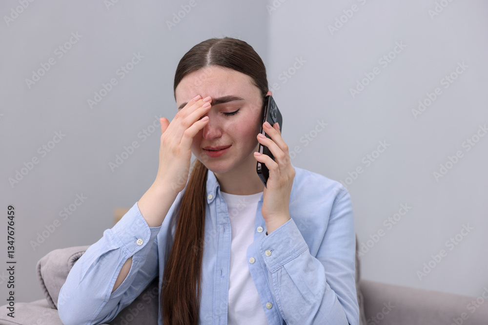 Stressed woman calling hotline for mental health help in armchair at home Stressed woman calling hotline for mental health help in armchair at home