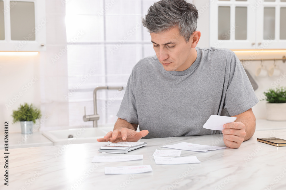 Paying bills. Man with different invoices using calculator at white marble table indoors Paying bills. Man with different invoices using calculator at white marble table indoors