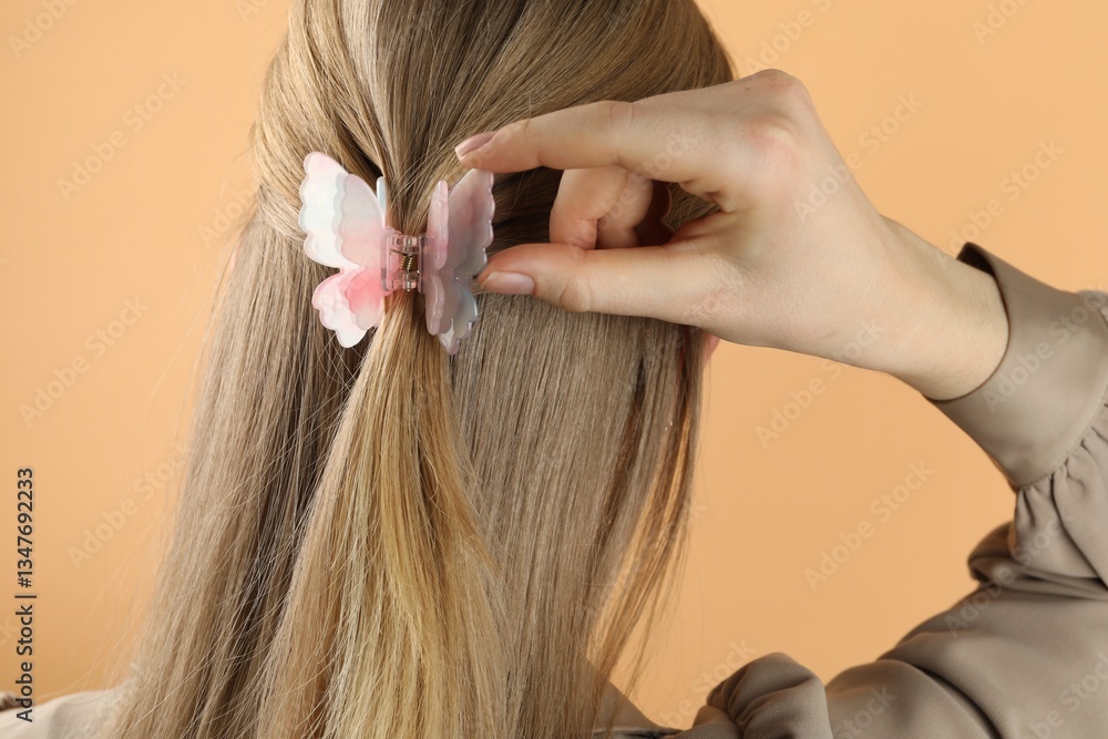 Woman with beautiful hair clip on beige background, back view