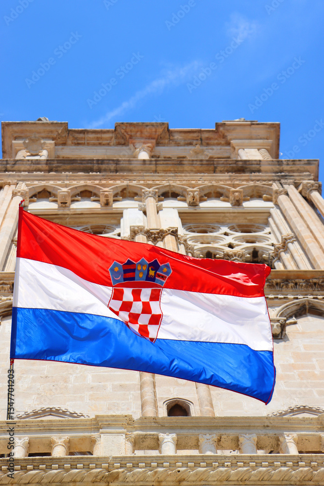 Croatian flag blowing in the wind on the bell tower of The Cathedral of St. Lawrence, landmark in Trogir, Croatia.