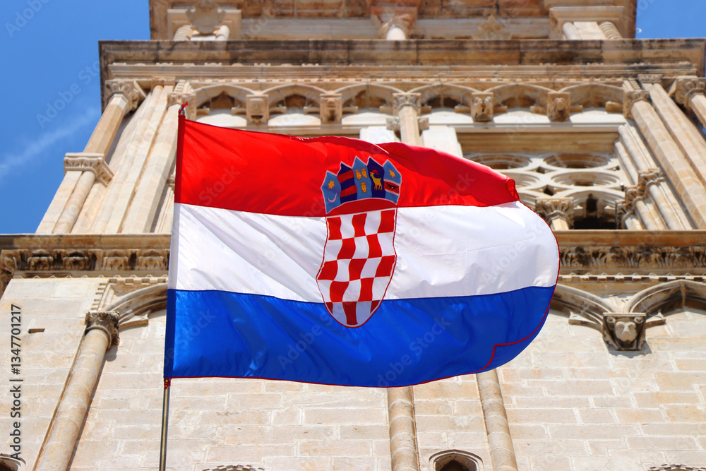 Croatian flag blowing in the wind on the bell tower of The Cathedral of St. Lawrence, landmark in Trogir, Croatia.