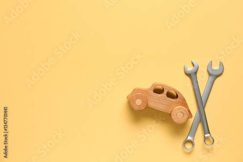 Wrenches and toy car on yel...