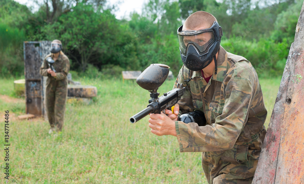 Fototapeta premium Group of friends paintball players of opposite teams in shootout in forest outdoors