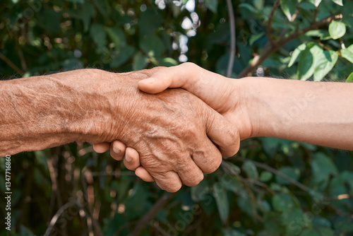 Handshake between an elderly and a young person, symbolizing connection, trust, and intergenerational support.