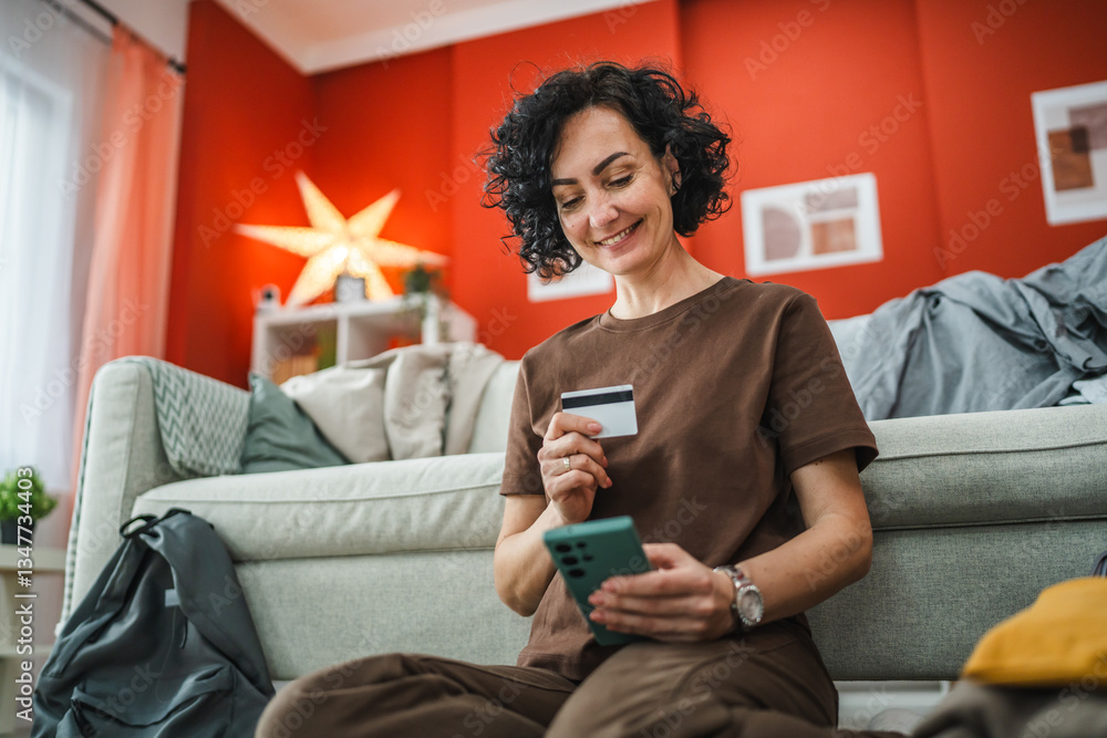 Obraz premium woman sit on floor near suitcase and have online shopping on cellphone
