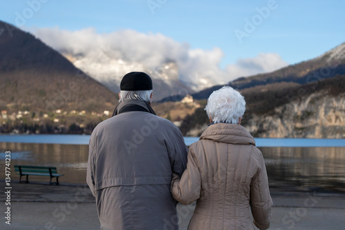 Elderly Couple Holding Hands, Facing Lake Annecy in Winter – Peaceful Retirement Moment in France
