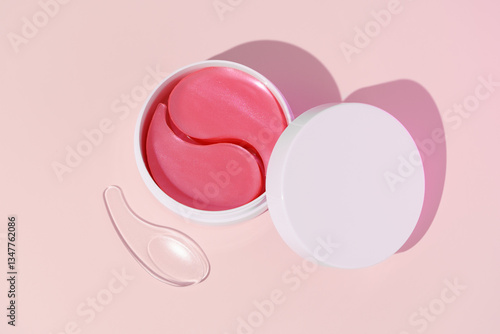 Top view of white mockup jar with pink hydrogel patches and spatula on pink isolated background. Concept of beauty products for skin care, dark circles reduction, hydration and nourishment