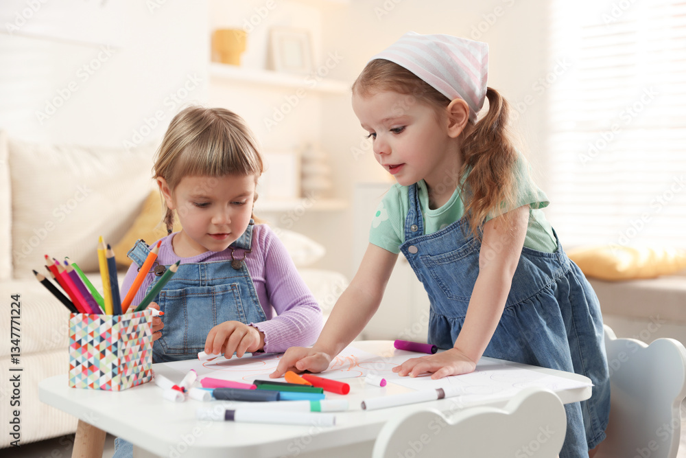 Fototapeta premium Cute little sisters drawing at white table in room