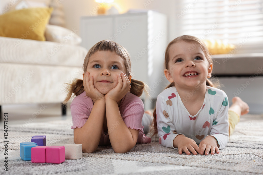 Fototapeta premium Cute little sisters lying on floor at home