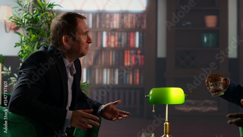 Obraz na plátně Two multiethnic businessmen sharing a whiskey glass in an elegant library, discussing business strategy and building trust