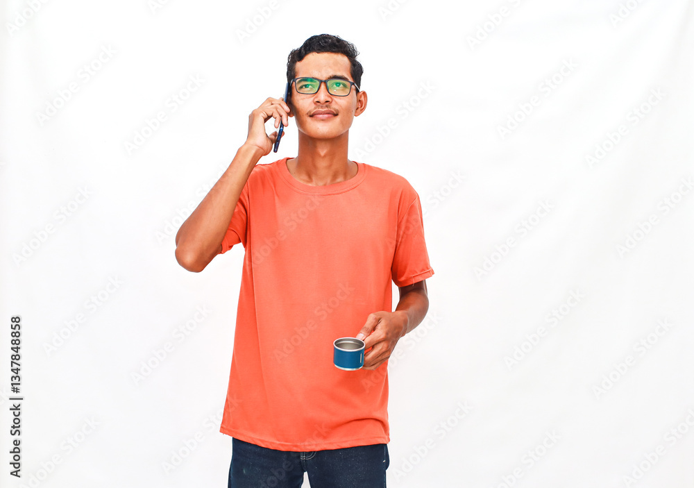 Young man in eyeglasses conversing on smartphone while sipping from metal cup Young man in eyeglasses conversing on smartphone while sipping from metal cup